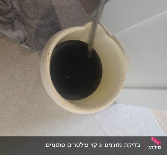 מים שחורים שנוקזו לדלי במהלך ניקוי עמוק של מזגן מעובש